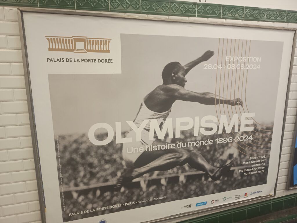 Poster of Olympisme: histoire du monde, 1896-2024 exhibition featuring black and white photograph of Jesse Owens jumping at the 1936 Berlin Olympics